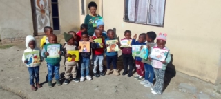 A practitioner and her learners from Sasalethu Day Care Centre showing off their donation of books